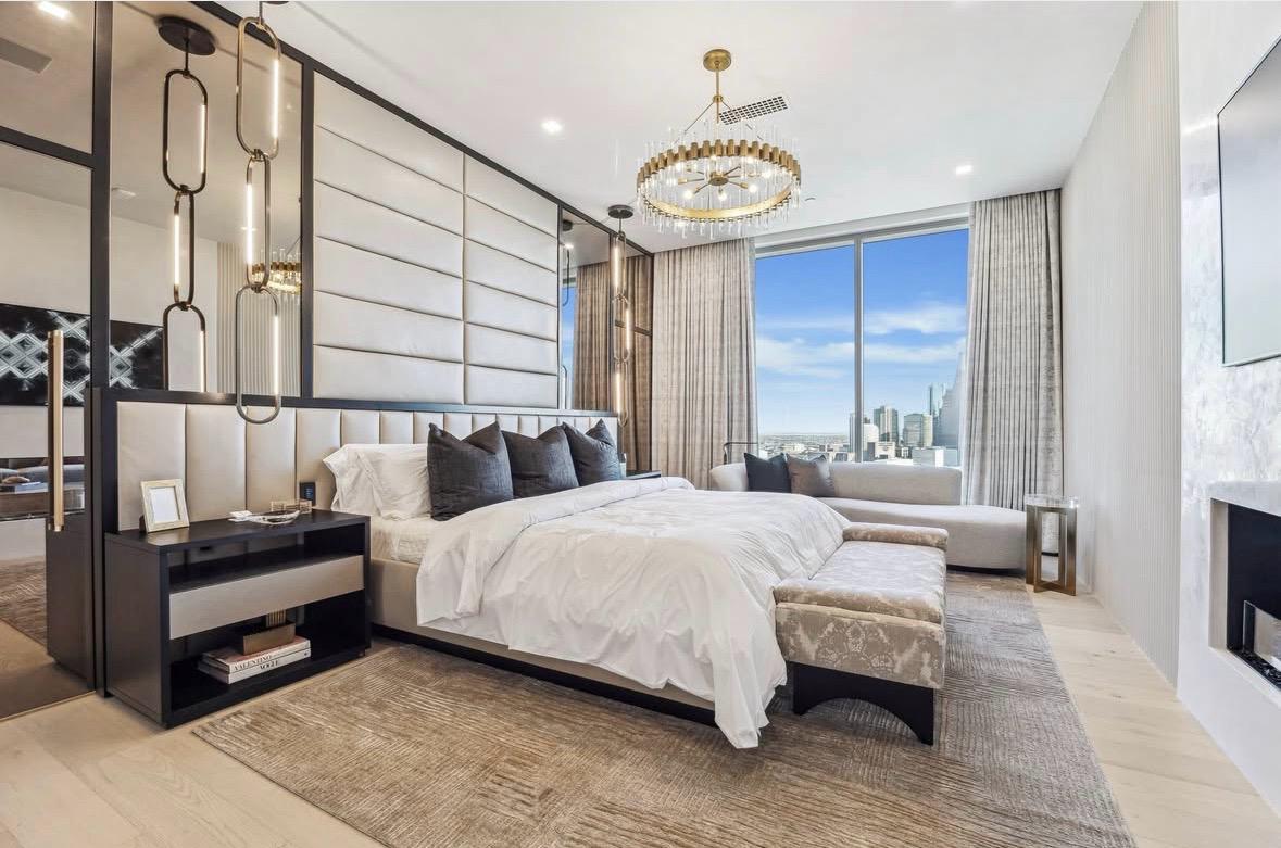 Primary bedroom with upholstered walls and a gold chandelier, The Residences at The Allen